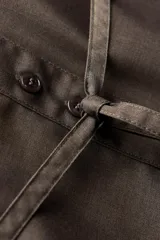 Camisa marrón de Zara Woman Collection, confeccionada en hilatura con viscosa. Tiene cuello solapa, manga larga con puño, bolsillo de plastrón en el pecho, cinturón ajustable con lazadas y bajo asimétrico. Se cierra con botones frontales.