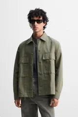 Sobrecamisa verde militar de algodón con estructura canvas, corte relaxed fit, cuello solapa, manga larga con puños abotonados, bolsillos frontales de plastrón con solapa, efecto lavado y cierre frontal con botones.