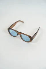 Lentes de sol con montura gruesa color marrón y lentes celestes.