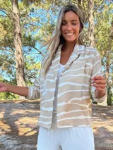 Camisaco de seda con estampado de rayas horizontales irregulares en tonos tierra y crudo. Posee cuello solapa y botones frontales.