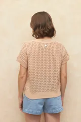 Chaleco tejido color beige con diseño calado, cuello redondo y mangas cortas.
