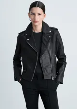 Campera de cuero ovino negra, estilo biker, con cuello con solapa, cierre frontal asimétrico con cremallera, mangas largas con cremallera en los puños y dos bolsillos laterales con cremallera. Tiene forro interior.