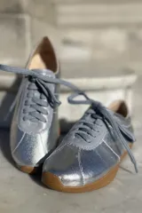 Zapatillas bajas con estampado animal print en blanco, marrón y negro, con puntera y talón en cuero color crema y suela de goma color caramelo.
