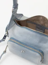 Bandolera azul de cuero vacuno con correa de hombro ajustable. Tiene cierre superior y bolsillos externos con cierre en el frente, dorso y laterales.