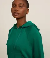Campera deportiva verde esmeralda de modal, con capucha ajustable con cordón, cierre frontal con cremallera y bolsillos laterales.