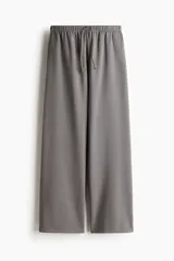 Pantalón de jogging gris de corte holgado, con cintura elástica ajustable con cordón, bolsillos laterales y piernas anchas.
