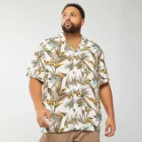 Camisa de manga corta con estampado de hojas en tonos verdes, marrones y celestes sobre fondo blanco.