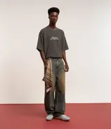 Pantalón super baggy de jeans con lavado dirty en tonos tierra, cintura con trabilla, cierre tradicional, bolsillos y bordado en el bolsillo trasero.