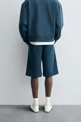 Bermuda azul petróleo de corte relaxed fit, confeccionada en algodón. Tiene cintura elástica ajustable con cordón, bolsillos laterales y un bolsillo trasero.