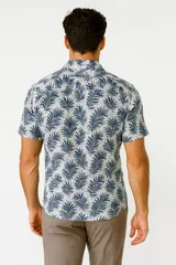 Camisa de viscosa con estampado de hojas de palmera en tonos azul y blanco, con cuello clásico y manga corta.