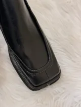Botas de cuero negras con punta cuadrada, taco bajo de madera y cierre lateral.