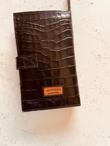 Billetera porta pasaportes de cuero sintético color marrón con textura tipo cocodrilo. Cuenta con cierre de broche y cierre de cremallera, múltiples ranuras para tarjetas y compartimentos para pasaportes y billetes.