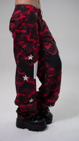 Pantalón de corte skinny, tiro bajo, con estampado camuflado en tonos rojo y negro, y estrellas blancas.