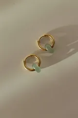 Par de aros tipo argolla dorados con dije de piedra natural con patrón de manchas negras sobre fondo blanco.