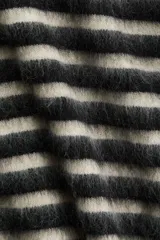 Buzo de punto suave con lana y mohair en la trama, diseño a rayas horizontales en blanco y negro, corte amplio con hombros caídos y terminaciones acanaladas.