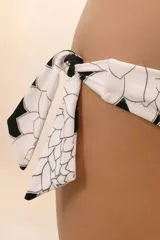Calzón de bikini negro con estampado de flores blancas y lazos laterales ajustables.