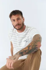 Remera de hombre a rayas horizontales blancas y beige, de manga corta, con bolsillo en el pecho y logo estampado.
