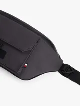 Riñonera o cangurera de color gris oscuro, confeccionada en poliuretano, con correa ajustable y cierre de hebilla. Presenta un compartimento principal con cremallera y un bolsillo exterior frontal con solapa.