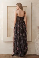 Vestido largo de fiesta negro con estampado floral multicolor, escote corazón, breteles finos, corpiño tipo corset con transparencias, falda con volados y tajo lateral.