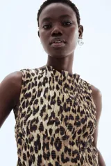 Top sin mangas con estampado animal print, corte ajustado, diseño punto smock, escote bote con volados y peplum.