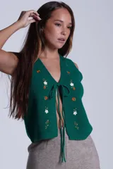 Chaleco tejido color crema con escote en V y cierre frontal con lazos. Presenta bordados de flores en tonos naranja, verde y blanco.