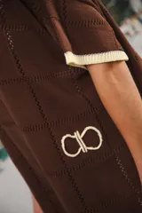 Vestido corto negro con patrón calado cuadrado, cuello redondo y mangas cortas con terminaciones a contratono en blanco.