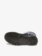 Bota biker Dr. Martens Anistone Harness, color negro, confeccionada en cuero Orleans. Presenta correas con hebillas y herrajes en plata envejecida, incluyendo una argolla metálica en el lateral. Cuenta con tirador con logo en la parte trasera y suela Bex ligeramente elevada.