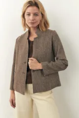 Chaqueta corta color marrón con cuello solapa, manga larga con coderas aplicadas, cierre frontal con botones y bolsillos ojal. Con forro. Tela 100% lana fina sin teñir, diseñada exclusivamente por Don Baez. Hecha 100% en Uruguay.