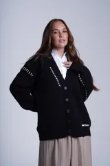 Cárdigan negro con botones, escote en V y detalles de costuras blancas en hombros, mangas y ruedo.