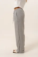 Pantalón holgado a rayas verticales en tonos gris y blanco, con cintura elástica ajustable mediante cordón.