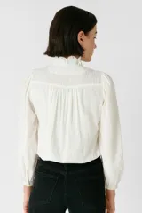 Camisa blanca de algodón con broderie, corte holgado, cuello mao y cierre frontal con botones.