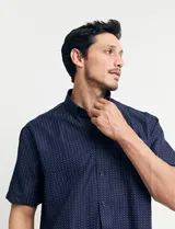 Camisa azul oscuro con pequeños lunares blancos, de manga corta y corte clásico.