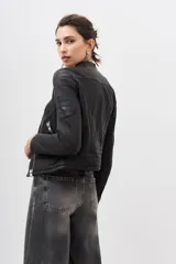 Campera negra de cuero ovino con cierre frontal asimétrico, cuello mao con botón a presión y bolsillos con cierre.