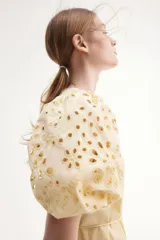 Vestido color crema a la rodilla, de tejido liviano de algodón con cuello redondo, botones ocultos adelante y cinturón fino extraíble. Mangas al codo abullonadas en broderie con puños elásticos.