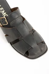 Zueco tipo cangrejera de cuero marrón oscuro, estilo mule (sin talón), con tiras trenzadas en la parte delantera y hebilla ajustable en el empeine.