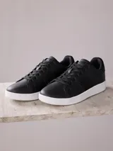 Championes negros de cuero sintético con suela blanca de goma.