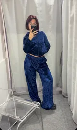 Conjunto deportivo de terciopelo azul, compuesto por campera con capucha y cierre frontal, y pantalón de corte ancho con cintura elástica.