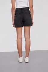 Bermuda de jean color negro con efecto lavado, tiro alto y corte holgado.