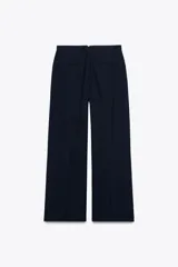 Pantalón de tiro medio color celeste confeccionado en hilatura con mezcla de lyocell. Tiene bolsillos laterales, pinzas delanteras, pierna ancha y cierre frontal con cremallera y botón.