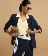 Blusa de punto color blanco, con cuello polo, escote en V y mangas cortas. Detalle de mini perlas aplicadas en el cuello.