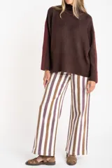 Sweater negro de tejido grueso con cuello alto acanalado. Presenta una franja decorativa en las mangas y el cuello en hilo marrón con brillo (lurex).