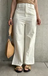 Pantalón de lino color crudo, de corte recto, con pinzas en la cintura y aberturas laterales en el ruedo.