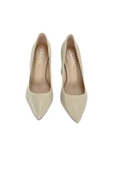 Zapatos de tacón color beige con punta fina y tacón geométrico que combina madera clara con detalles dorados.