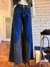 Pantalón jean wide leg con cintura alta, corte recto y diseño color block en azul y gris.