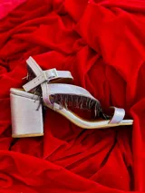 Sandalias plateadas con tiras finas y flecos colgantes, taco cuadrado y cierre con hebilla.