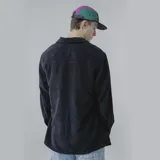 Camisa celeste de pana con corte oversize, cuello clásico, cierre frontal con botones, dos bolsillos con solapa en el pecho y mangas largas con puños abotonados.