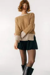 Sweater color camel con tejido de trenzas y terminaciones en color beige.