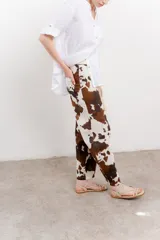Pantalón ancho de lino con estampado de manchas de vaca en tonos marrón y blanco. Incluye cinturón de soga trenzada con flecos.