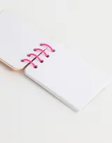 Llavero con forma de libreta con espiral, diseño de perro con manchas en relieve y fondo a rayas verticales.