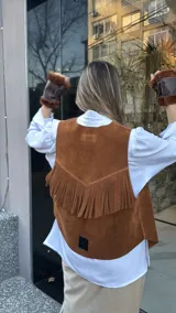 Chaleco marrón de cuero descarne con terminación en picos, tachas metálicas y flecos en la espalda.